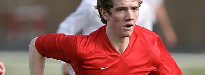 a male football player putting on a red jersey during a game